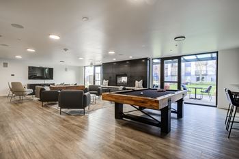 A room with a pool table and chairs.